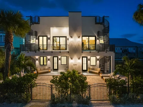Illuminated multilevel home at dusk with balconies and spiral staircases on both sides.